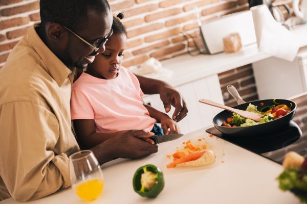 Dad and daughter cutting fresh vegetables for dinner