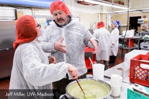 Two people discussing food production while cooking in a business kitchen.