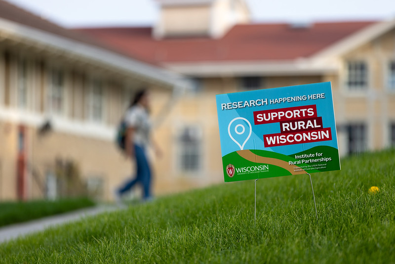 A yard sign for the Institute for Rural Partnerships is shown in a grassy area on the UW–Madison campus