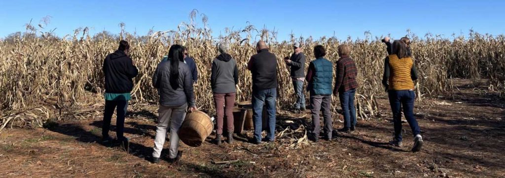 A group of people standing in front of a corn field ready to be harvested