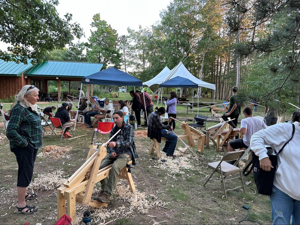 A group of people learning how to make lacrosse sticks and knocking sticks for harvesting wild rice.
