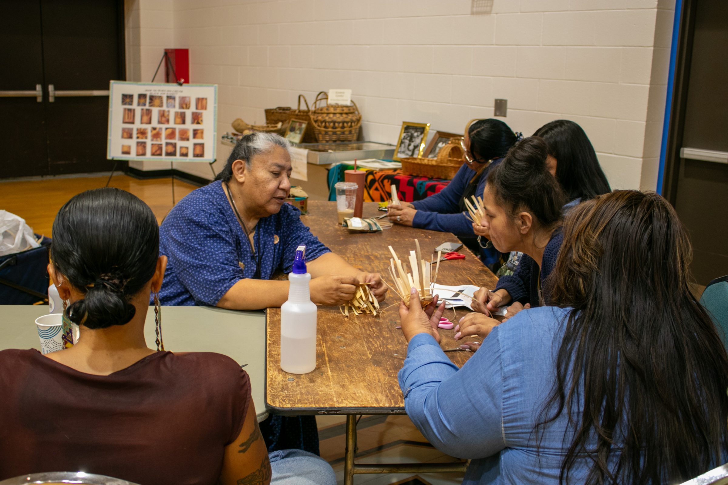 A group of people sitting together at a table learning how to make black ash baskets
